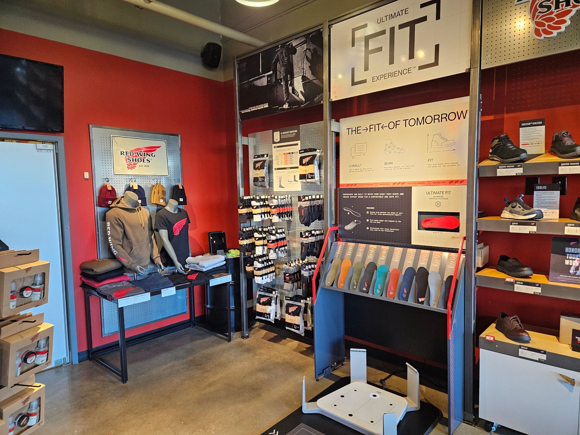 Interior of a store, red wall, shoe displays, and a sign that says 
