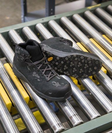 Black boots on a roller conveyor belt.