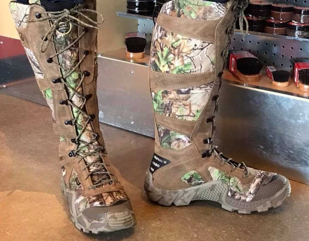 Tall, brown camouflage hunting boots with laces, set on a tan floor.