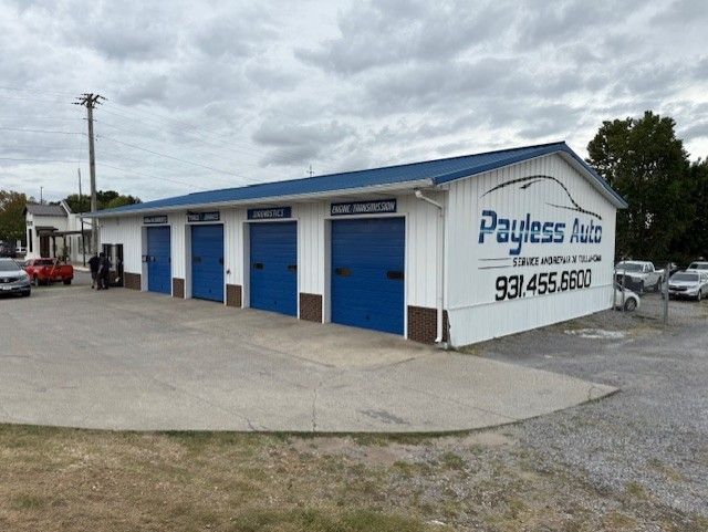 A white building with blue doors and a sign that says payless auto