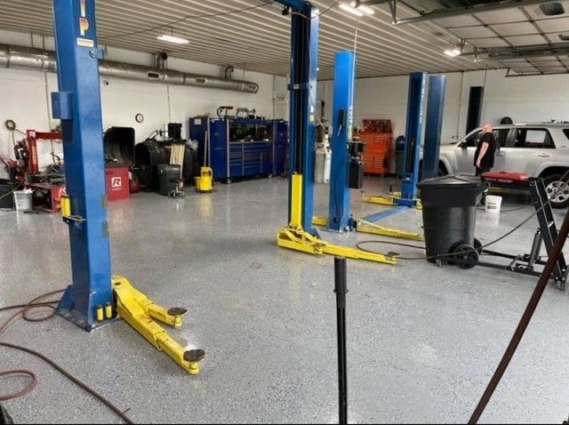A garage with a lot of lifts and a car in the background