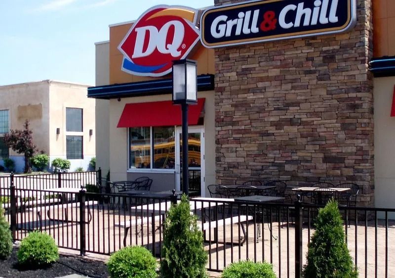 Dairy Queen Grill & Chill restaurant exterior with outdoor seating and a black fence.