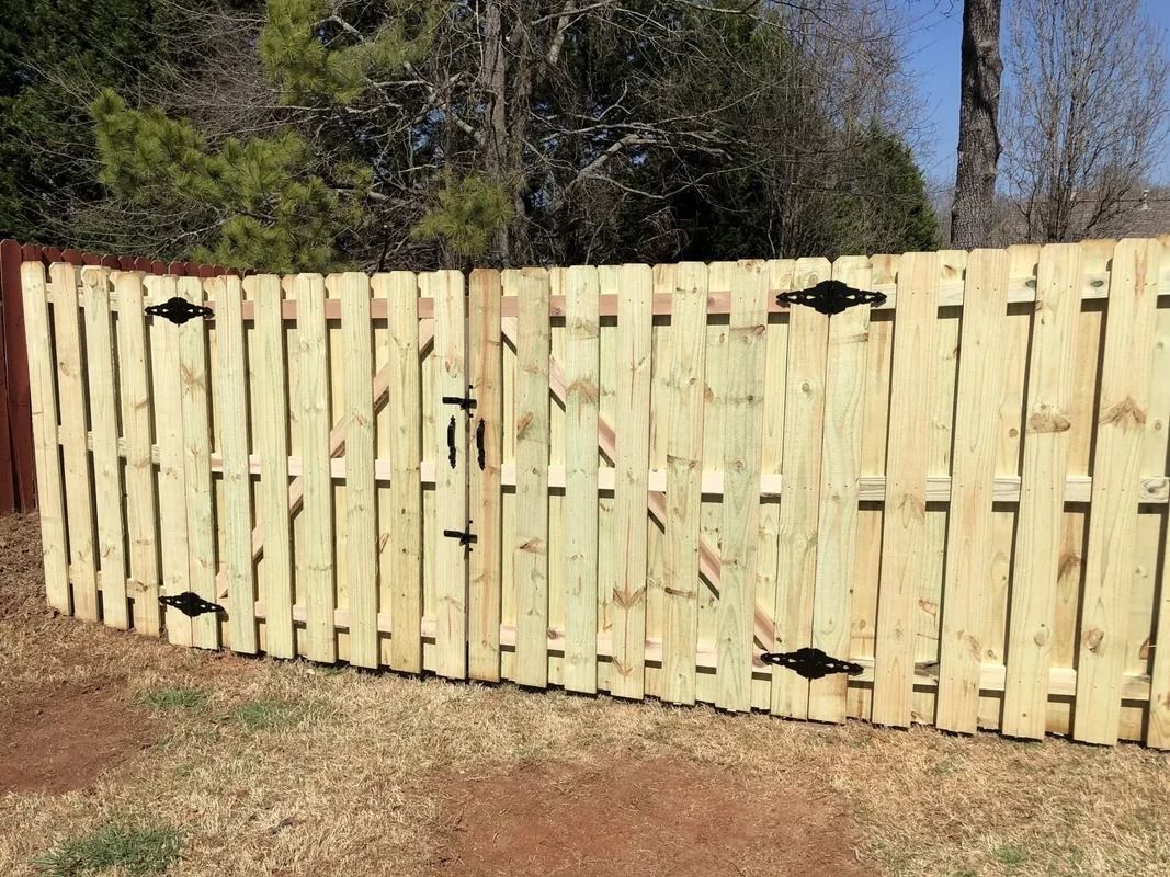 Wooden picket fence with gate, metal hinges and latch, outdoors in a yard.