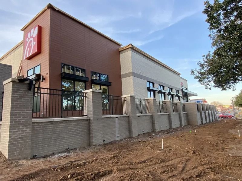 New Chick-fil-A under construction, featuring brick exterior, drive-through, and red logo against a blue sky.