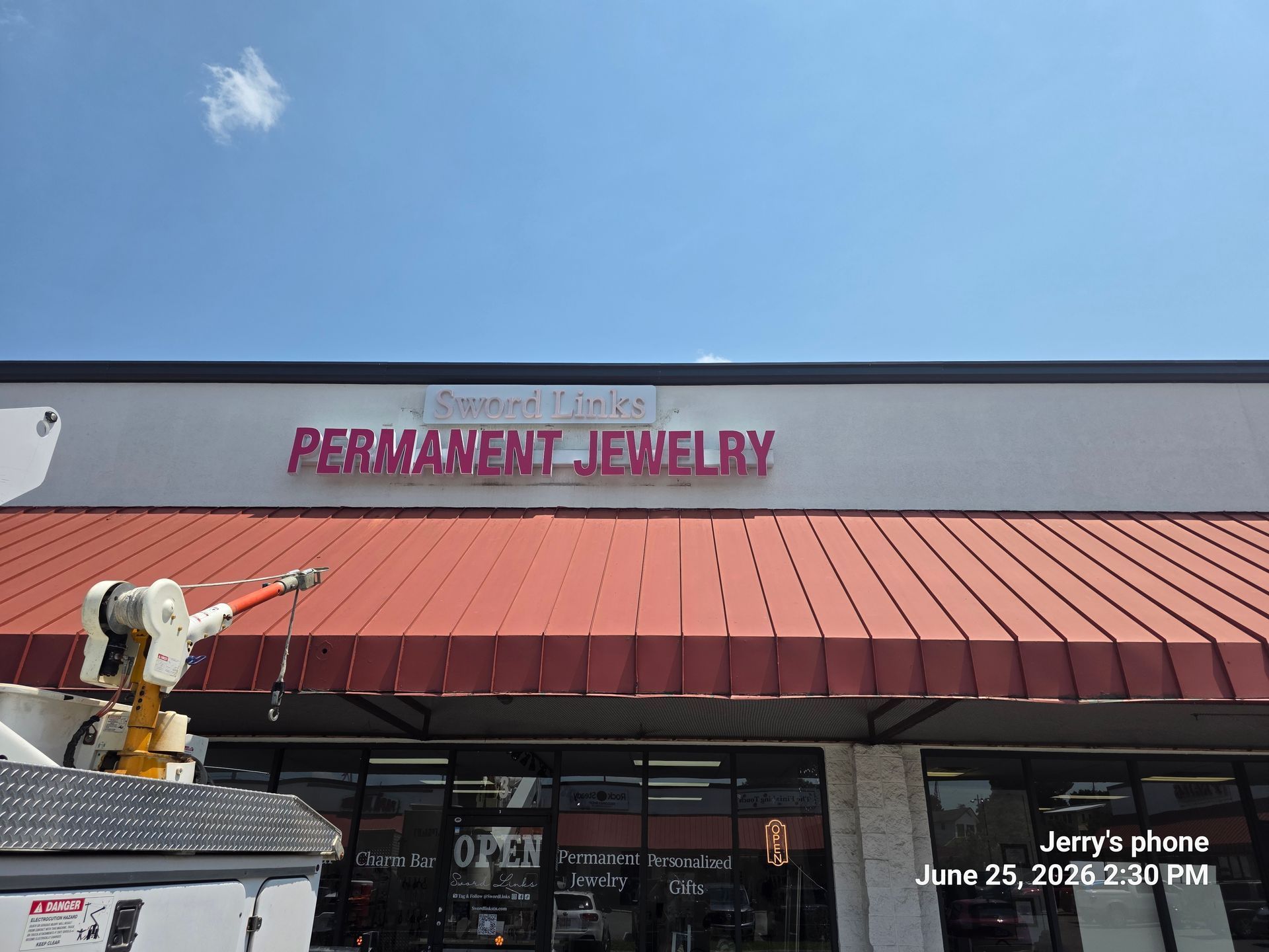 Storefront of Permanent Jewelry with a red awning and clear blue sky above