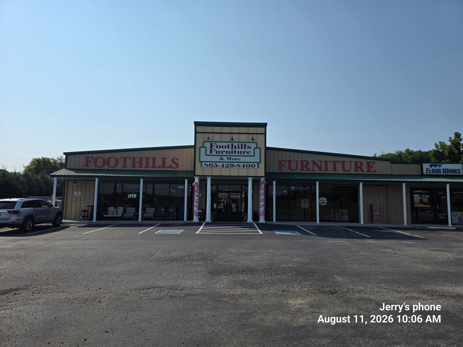 Front view of a furniture store with a parking lot and clear blue sky.