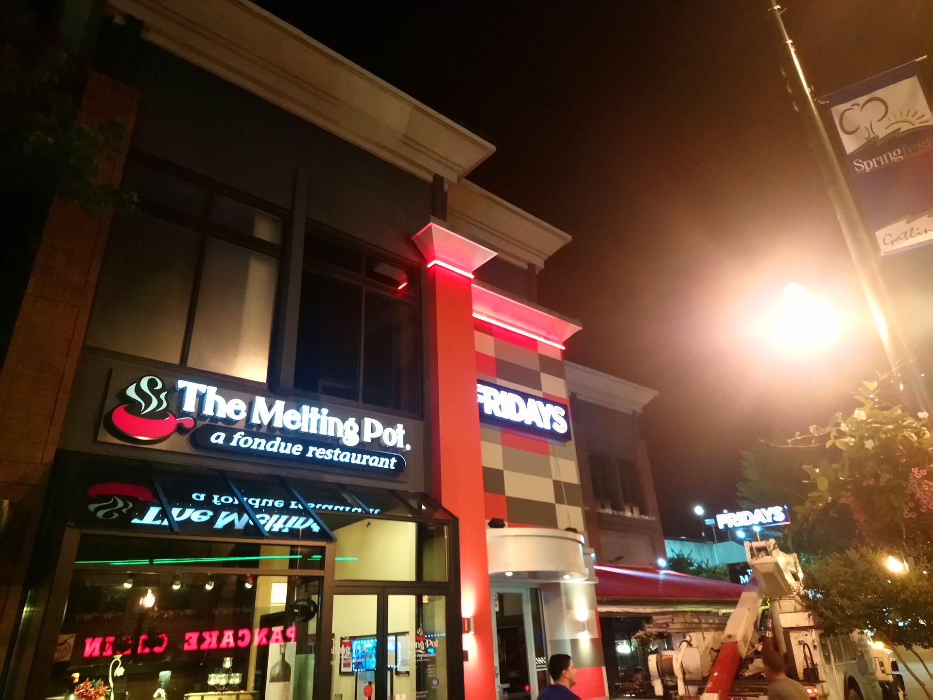The Melting Pot restaurant storefront at night with red neon lights and street scene