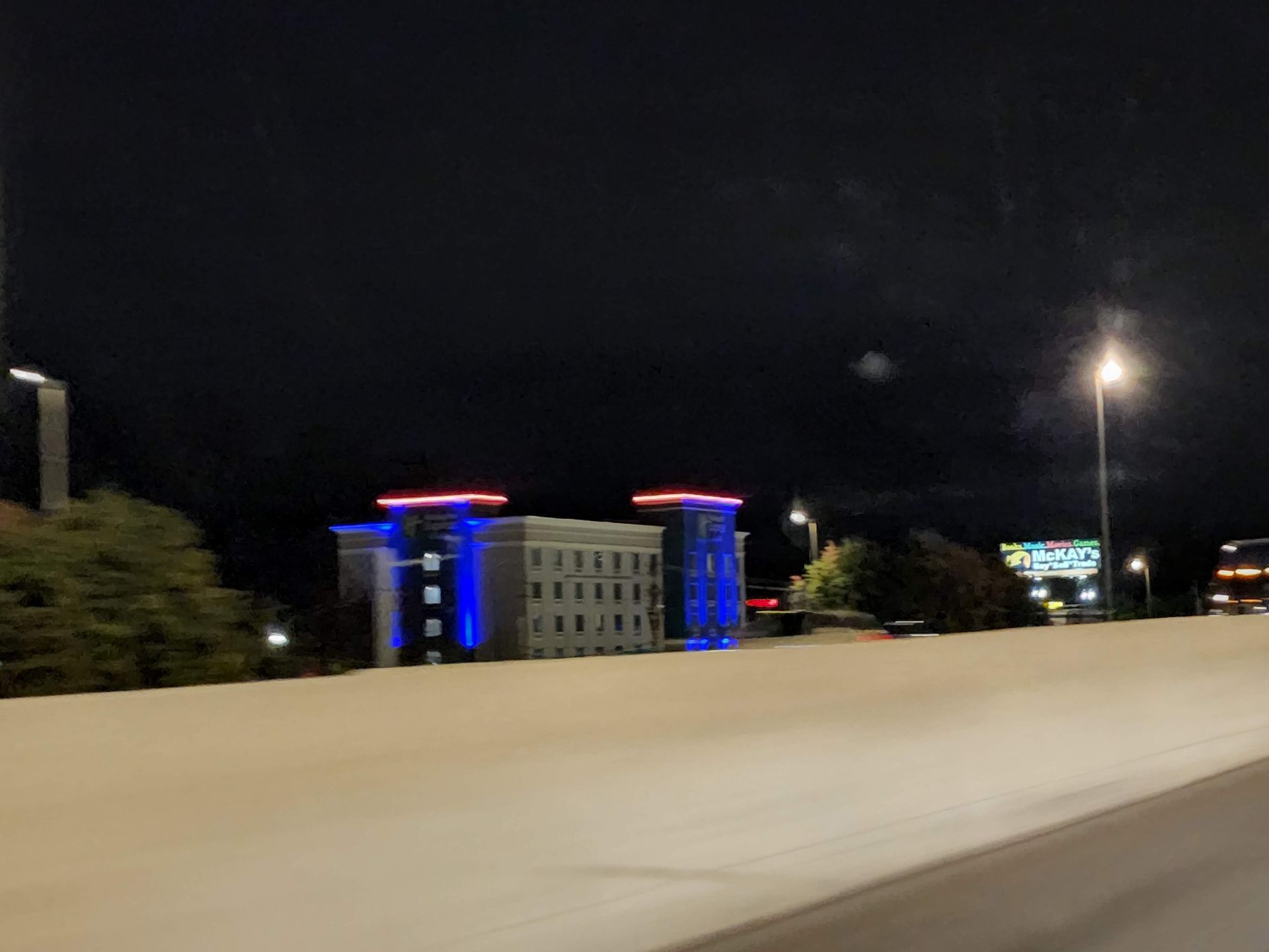 Night highway view with a lit building glowing blue and red against a dark sky