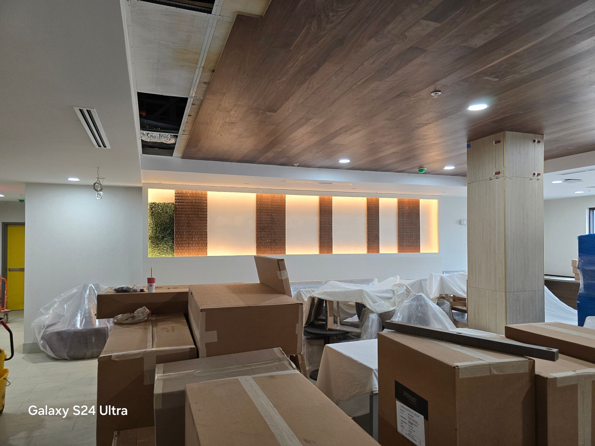 Interior room under renovation with stacked cardboard boxes and covered furniture under warm ceiling lights