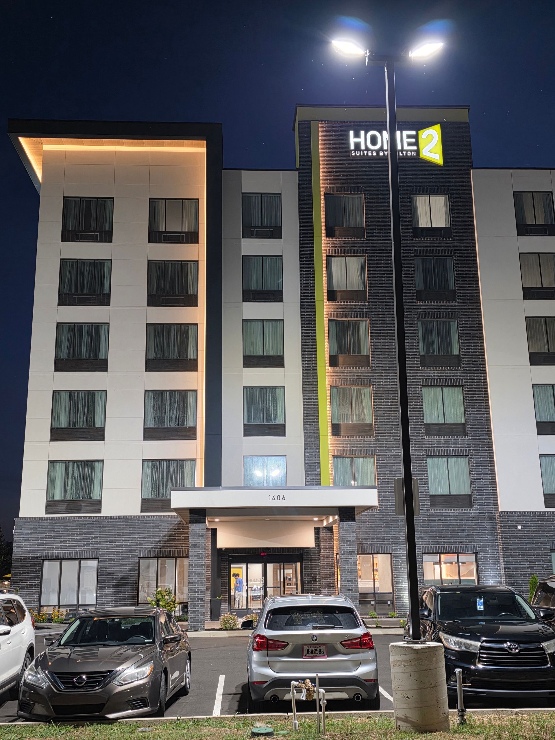 Hotel building at night with lit windows and parked cars in front