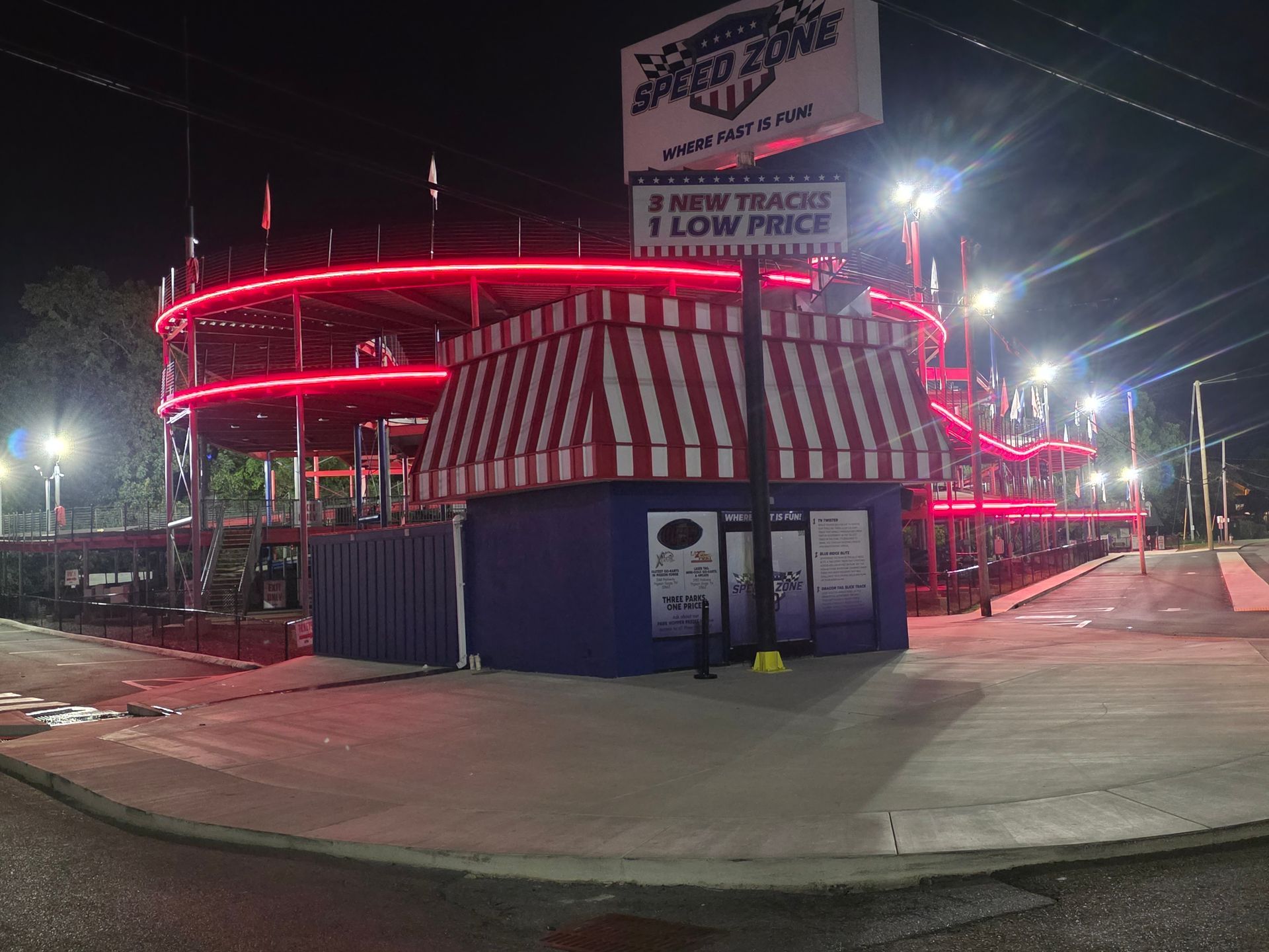 Neon-lit red-and-white striped building at night with a large sign and closed storefronts.