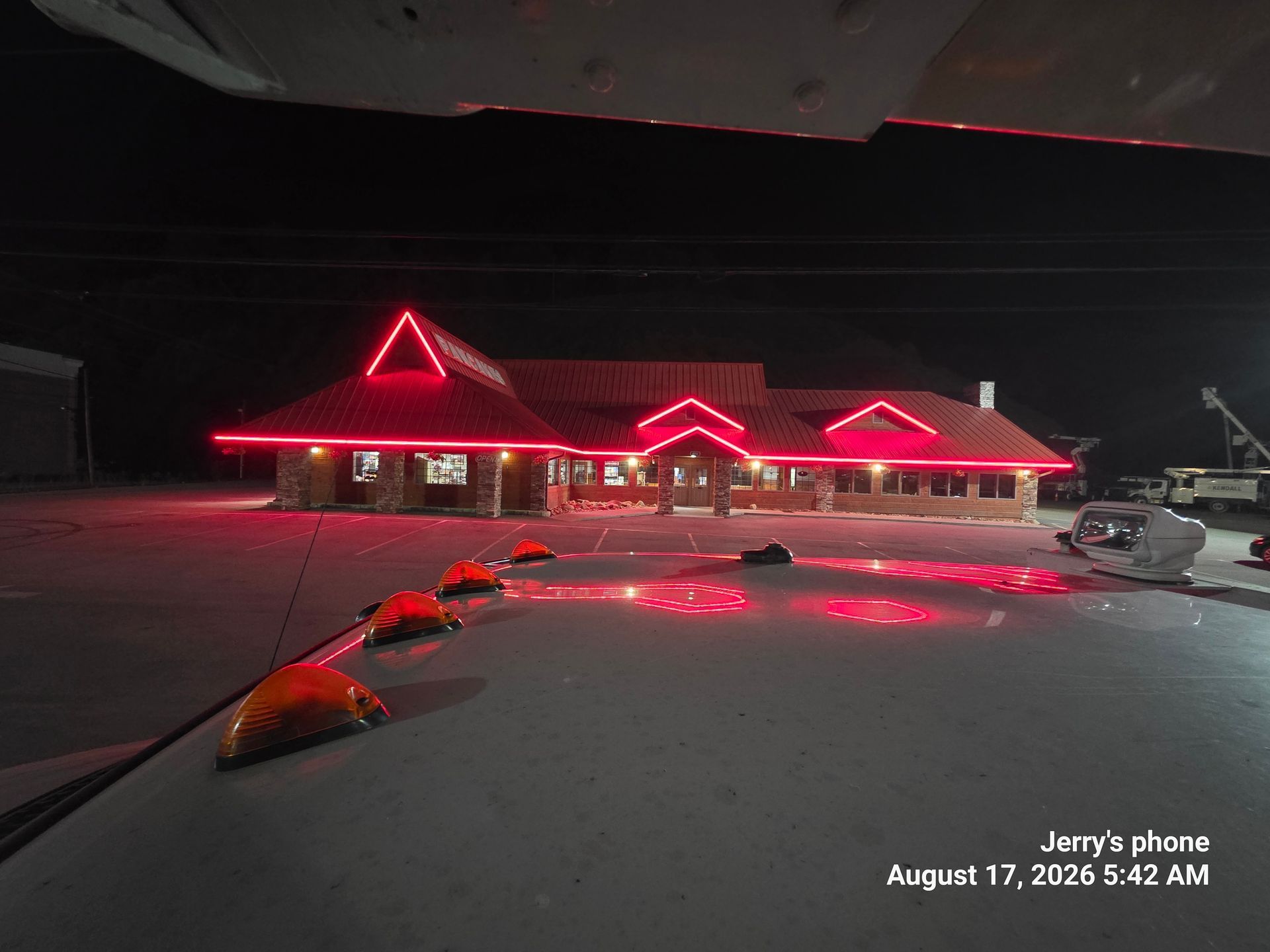 Snowy roadside restaurant at night, lit by red neon lights and reflections on the ground.