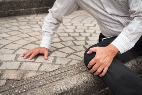 A man is kneeling down on a set of stairs.