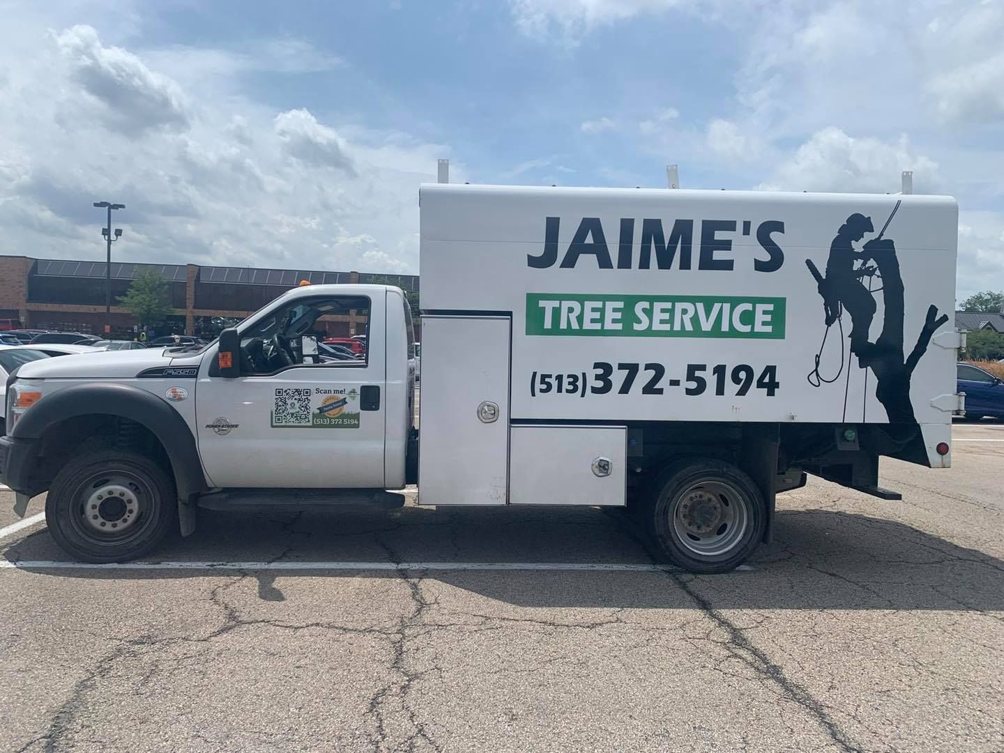 White truck for Jaime's Tree Service with logo and phone number. Parked in a lot, under a cloudy sky.