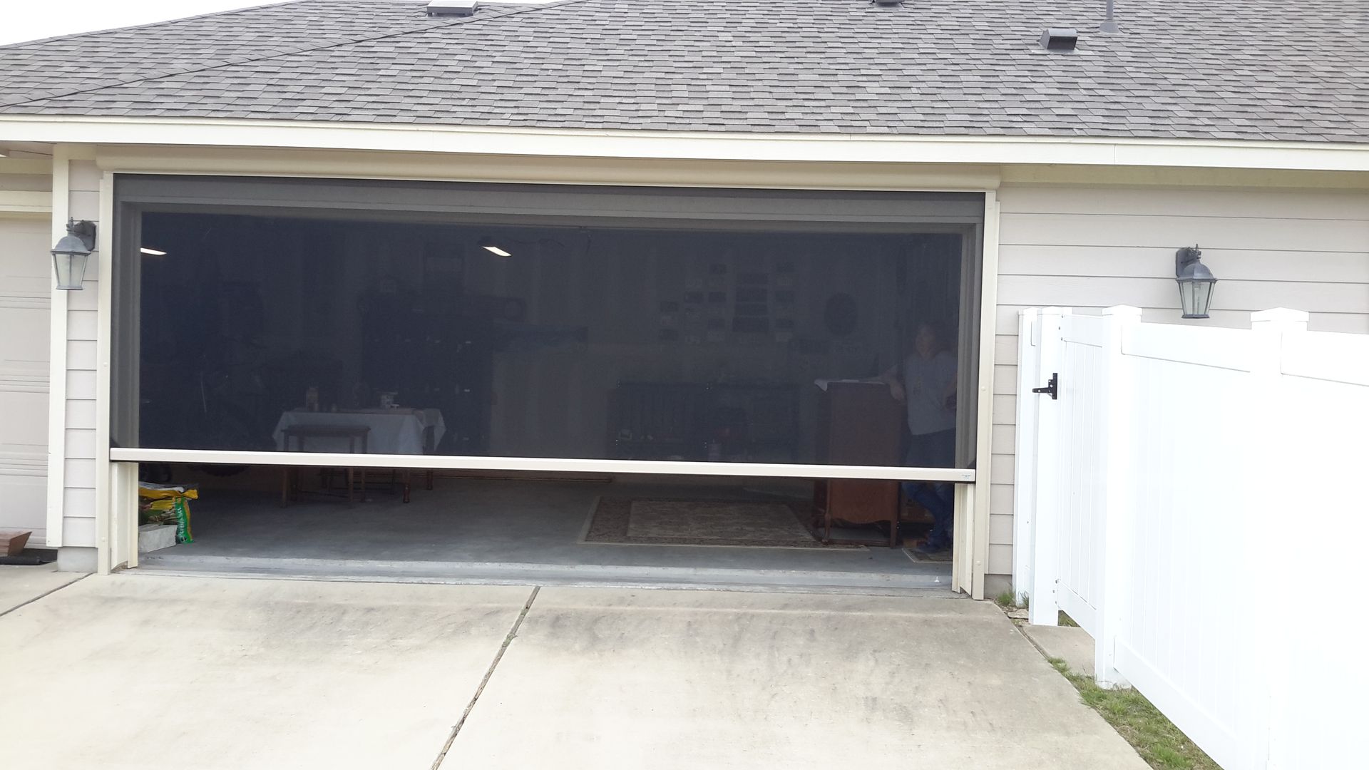 a garage door is open and a white fence is in the background .