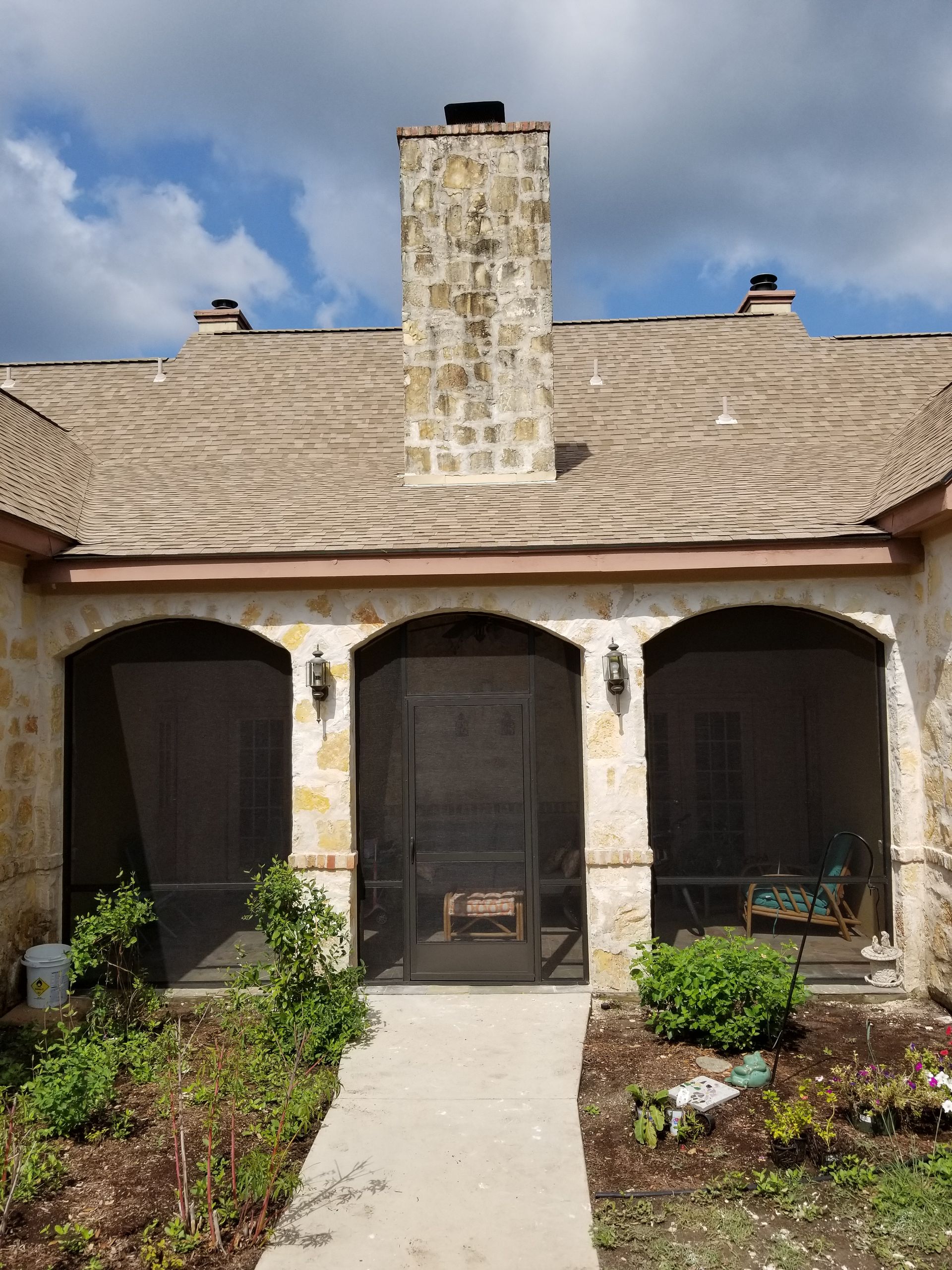 a stone house with a screened in porch and a chimney .