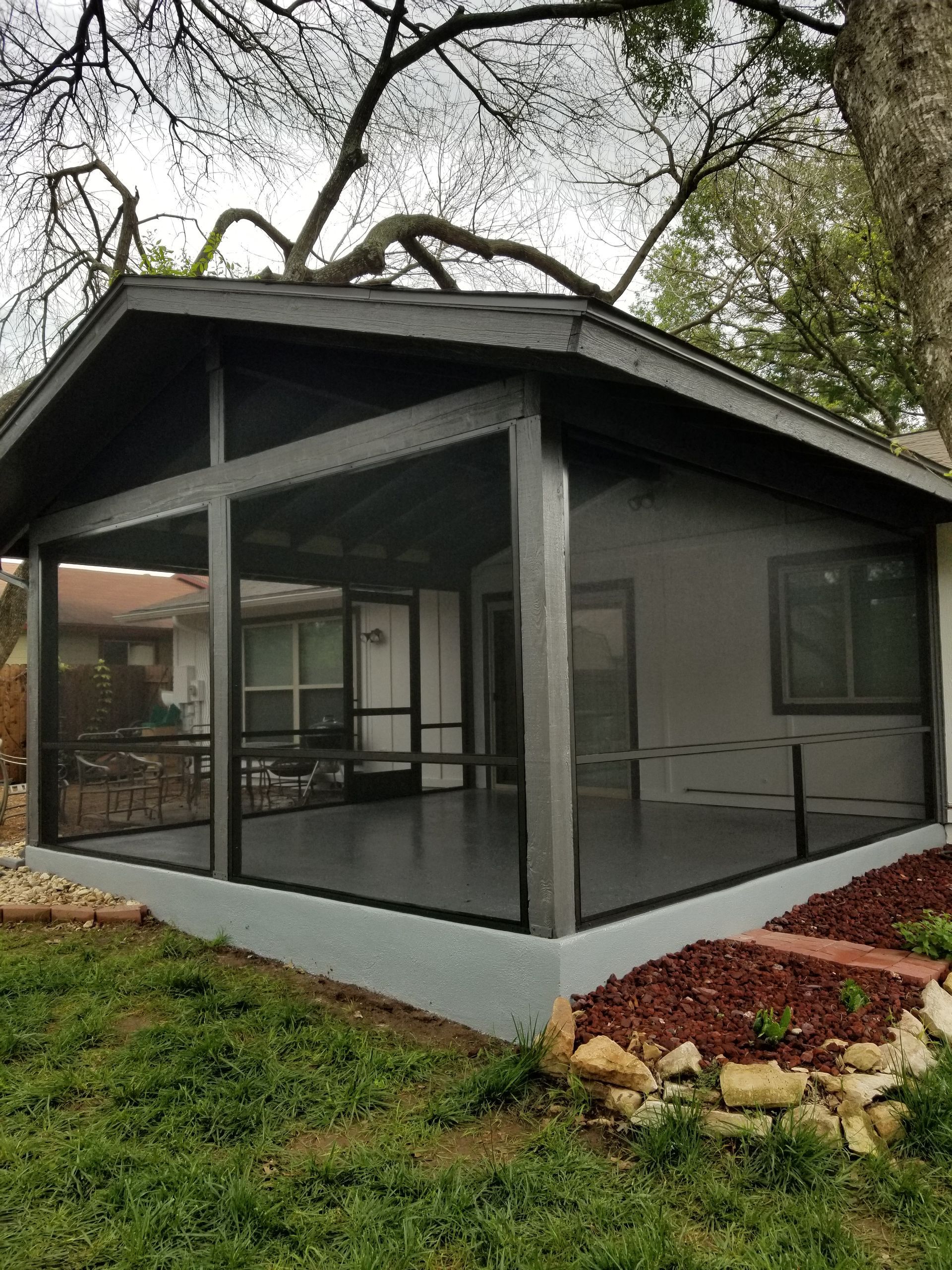 a screened in porch in the backyard of a house .