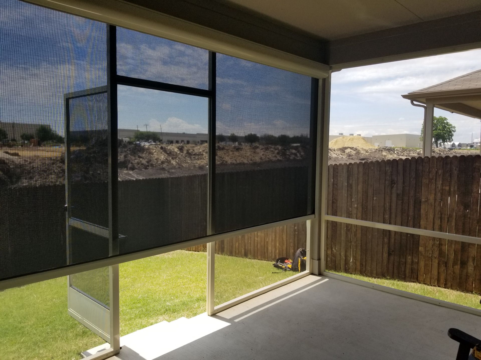 a screened in porch with a fence in the background .