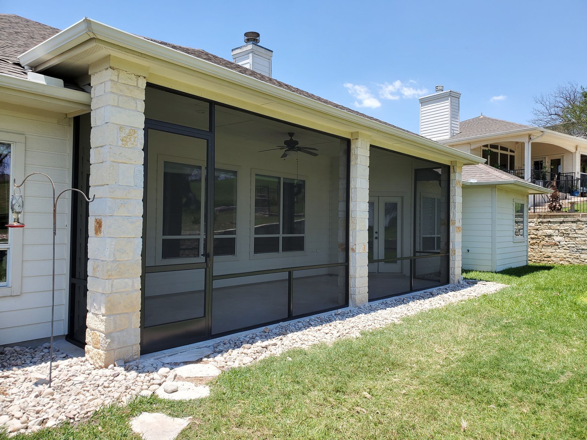 a screened in porch with a ceiling fan on the side of a house .