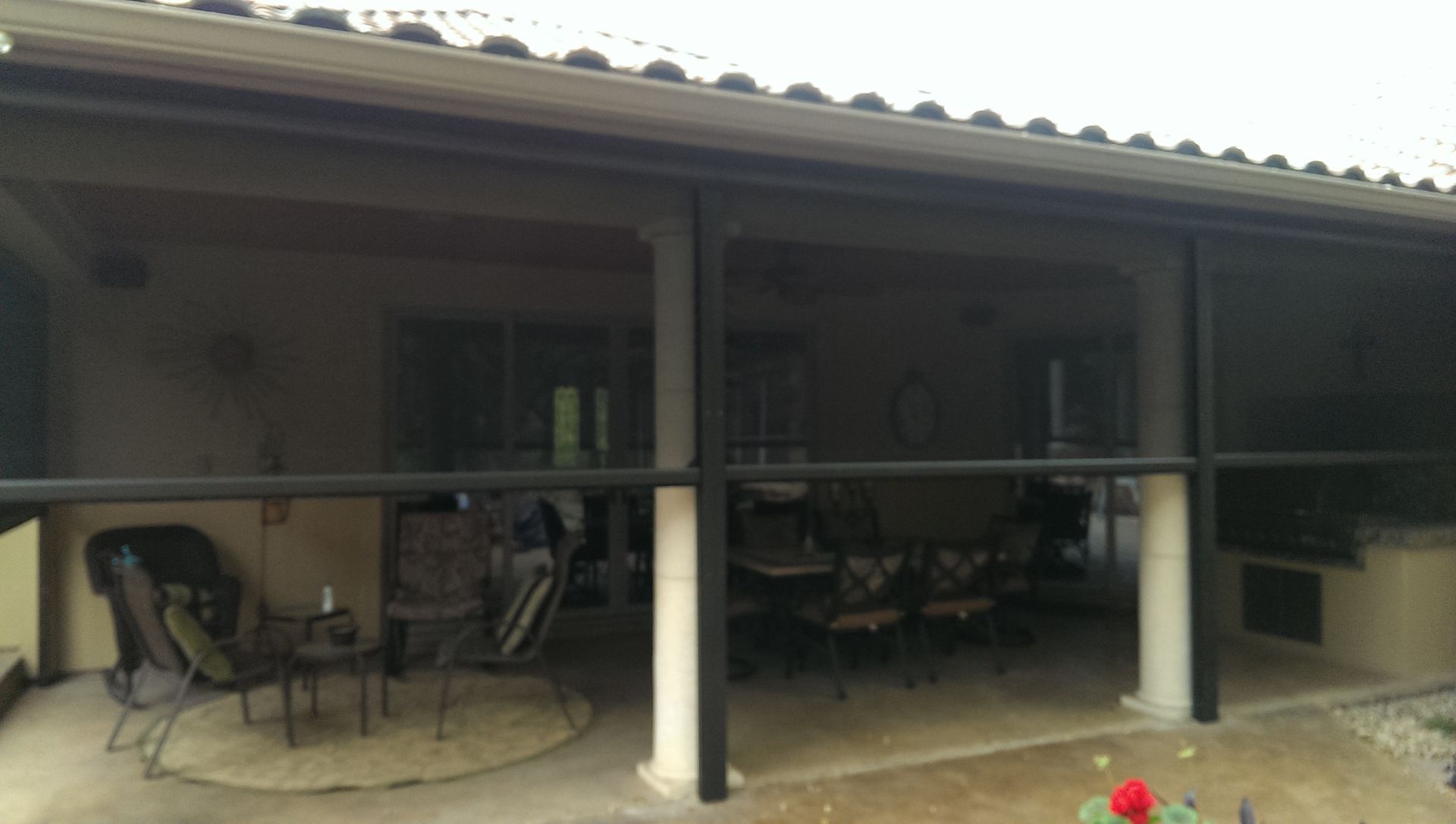 a screened in porch with a table and chairs on it .