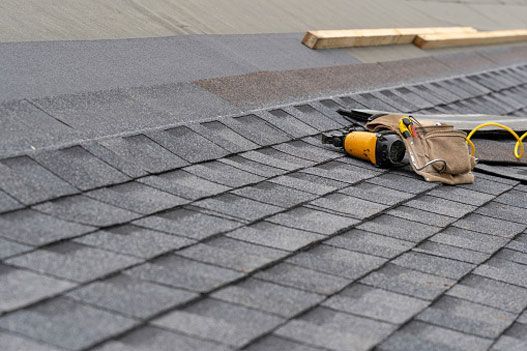 a roof with shingles being installed and tools on it