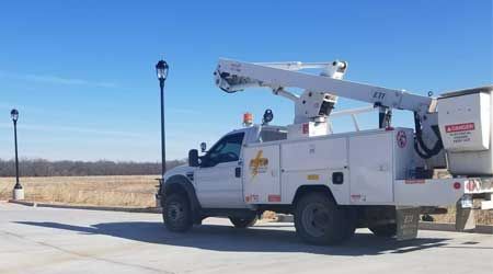 a white utility truck with a crane on the back is parked on the side of the road