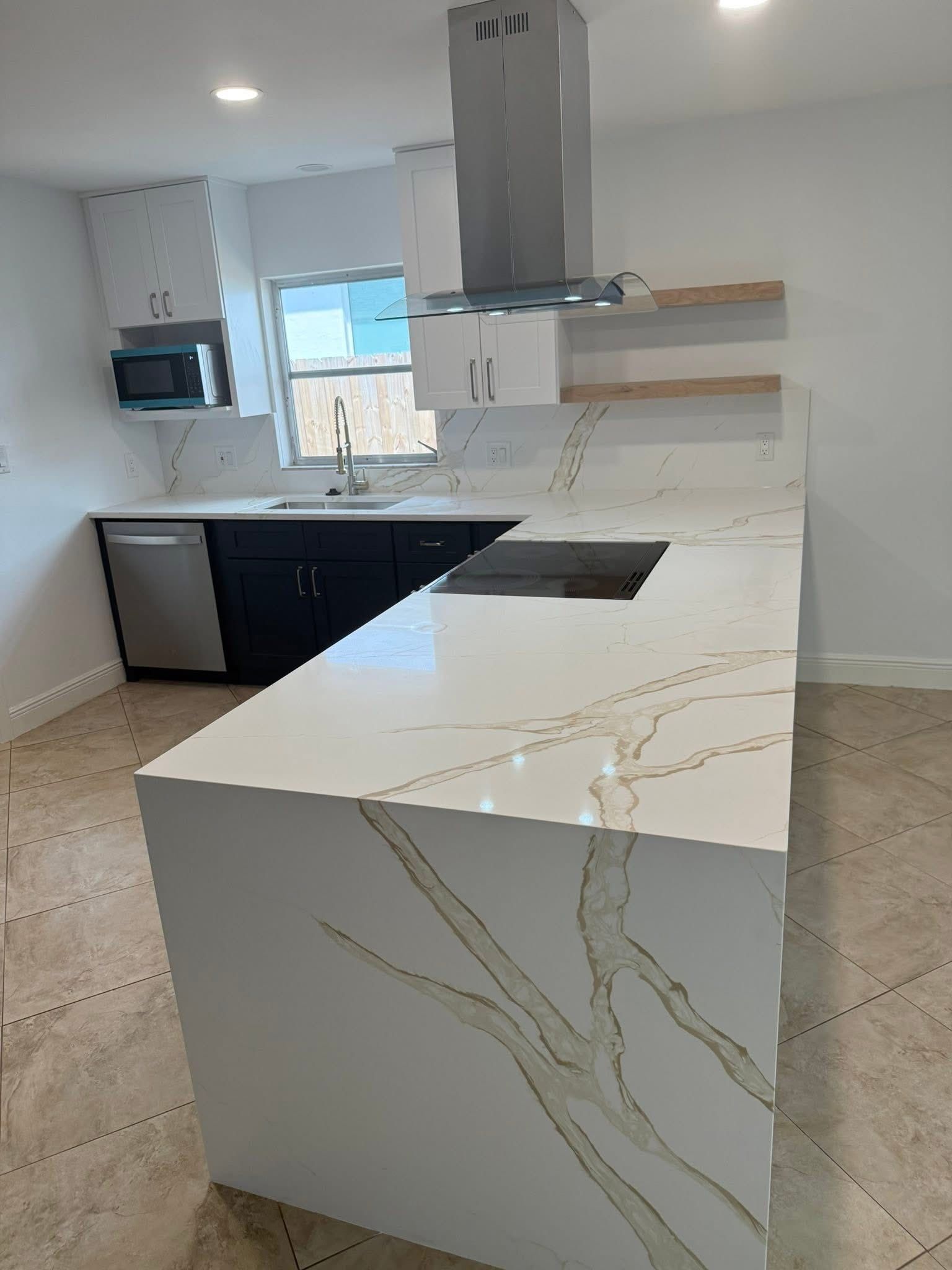 Modern kitchen with white quartz countertop island, stainless steel appliances, and black cabinetry.