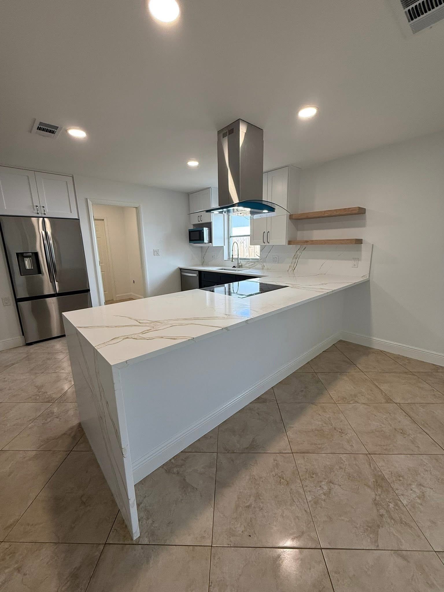 Modern kitchen with white countertops, stainless steel appliances, and island.