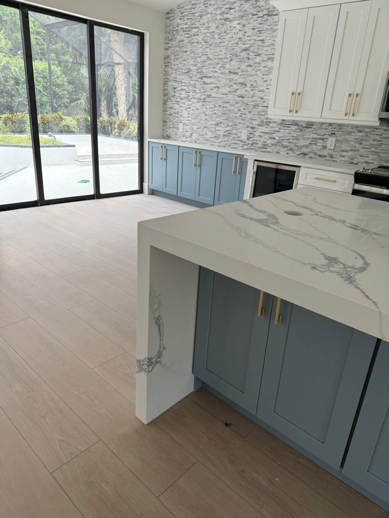 Modern kitchen with blue cabinets, white countertops, and sliding glass doors.