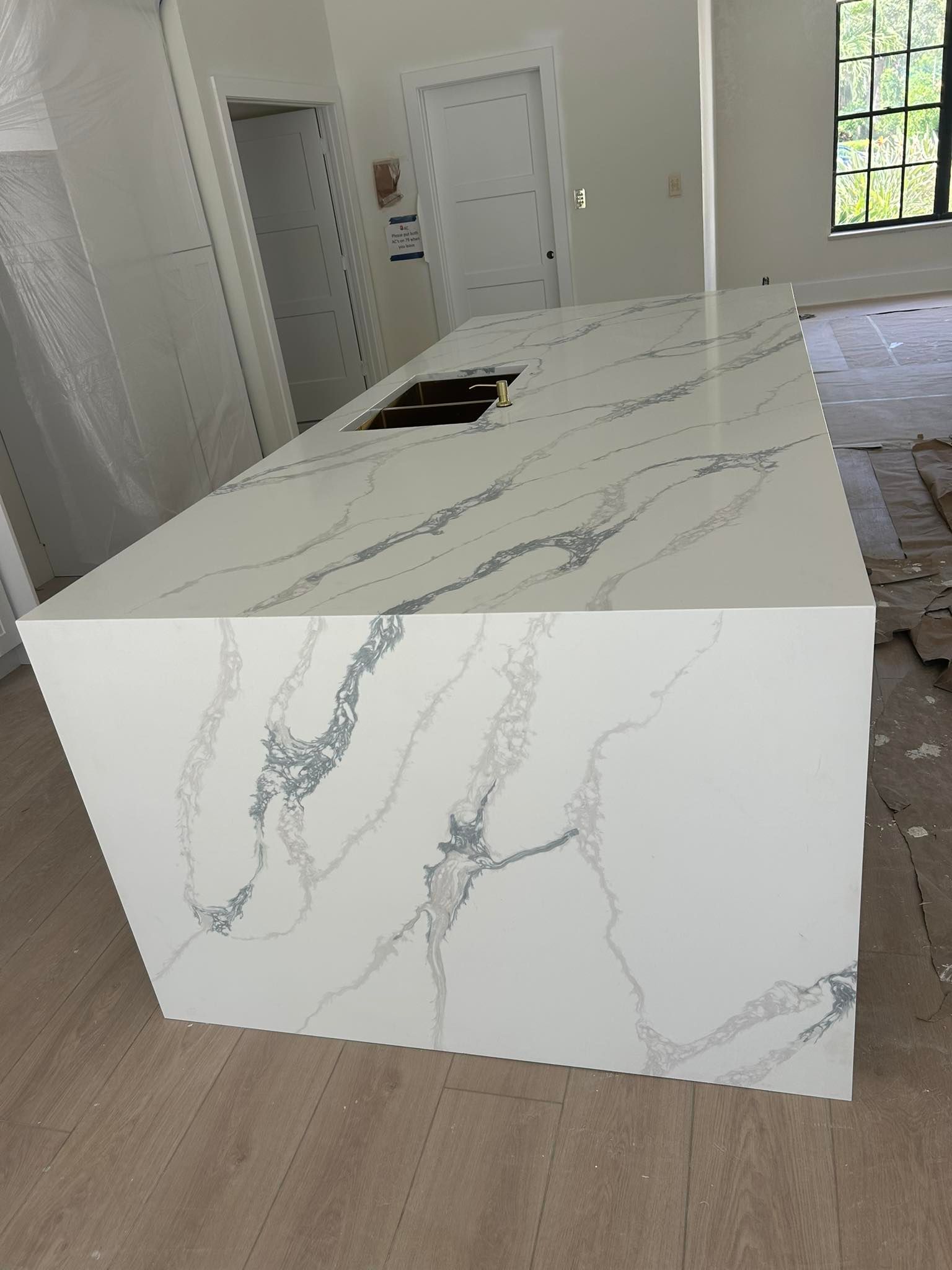 White kitchen island with grey veining, incomplete construction.