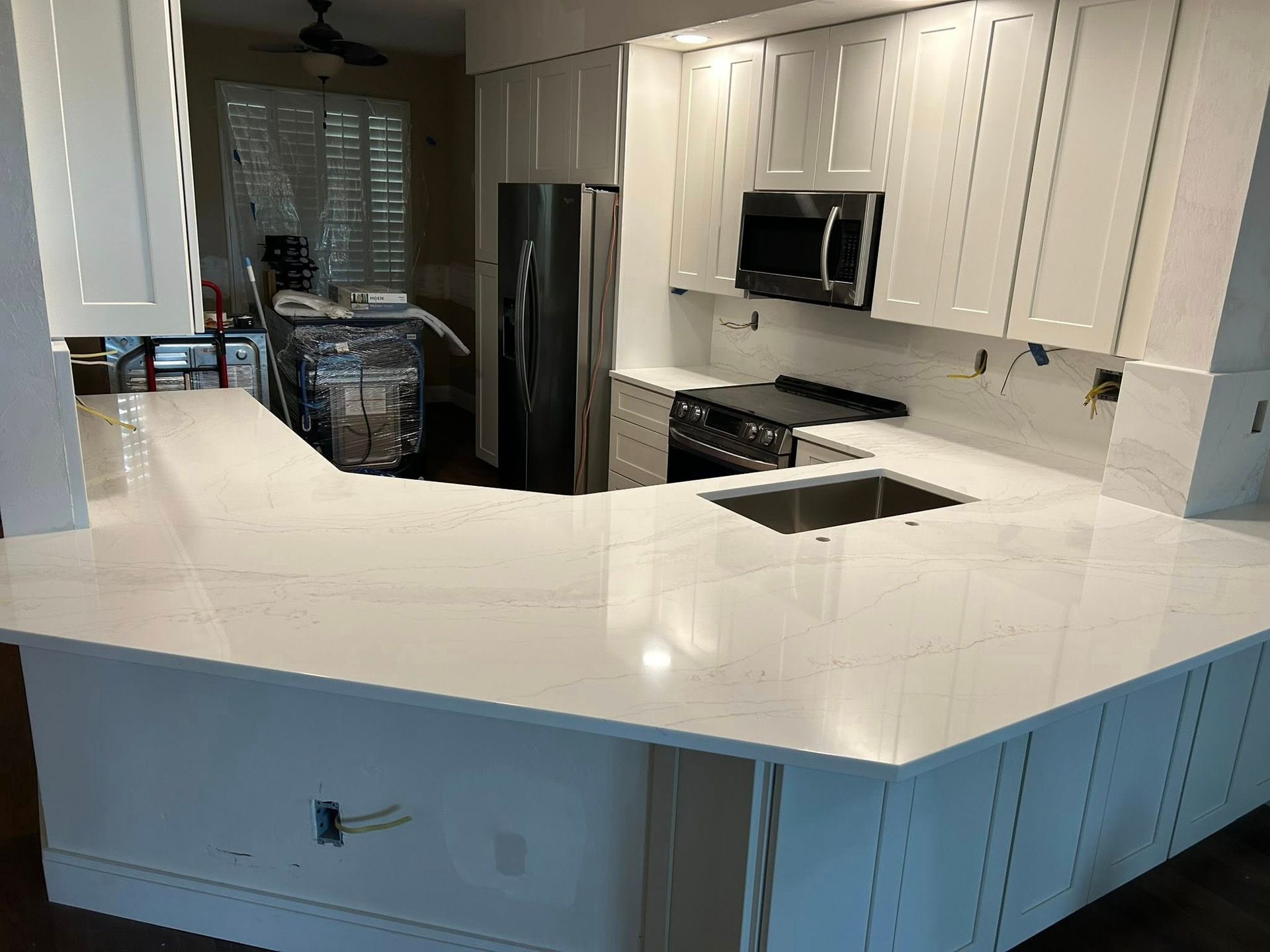 White kitchen with quartz countertops and stainless steel appliances.
