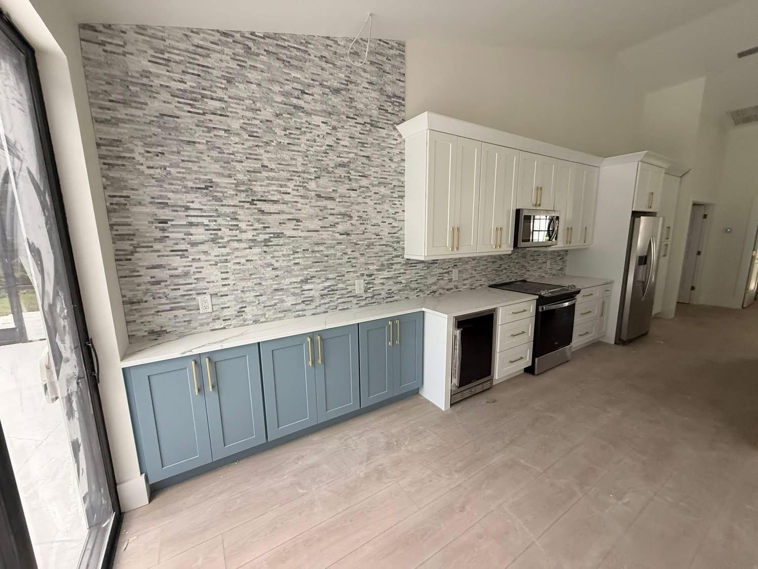 Kitchen with light blue and white cabinets, white countertops, and textured backsplash.