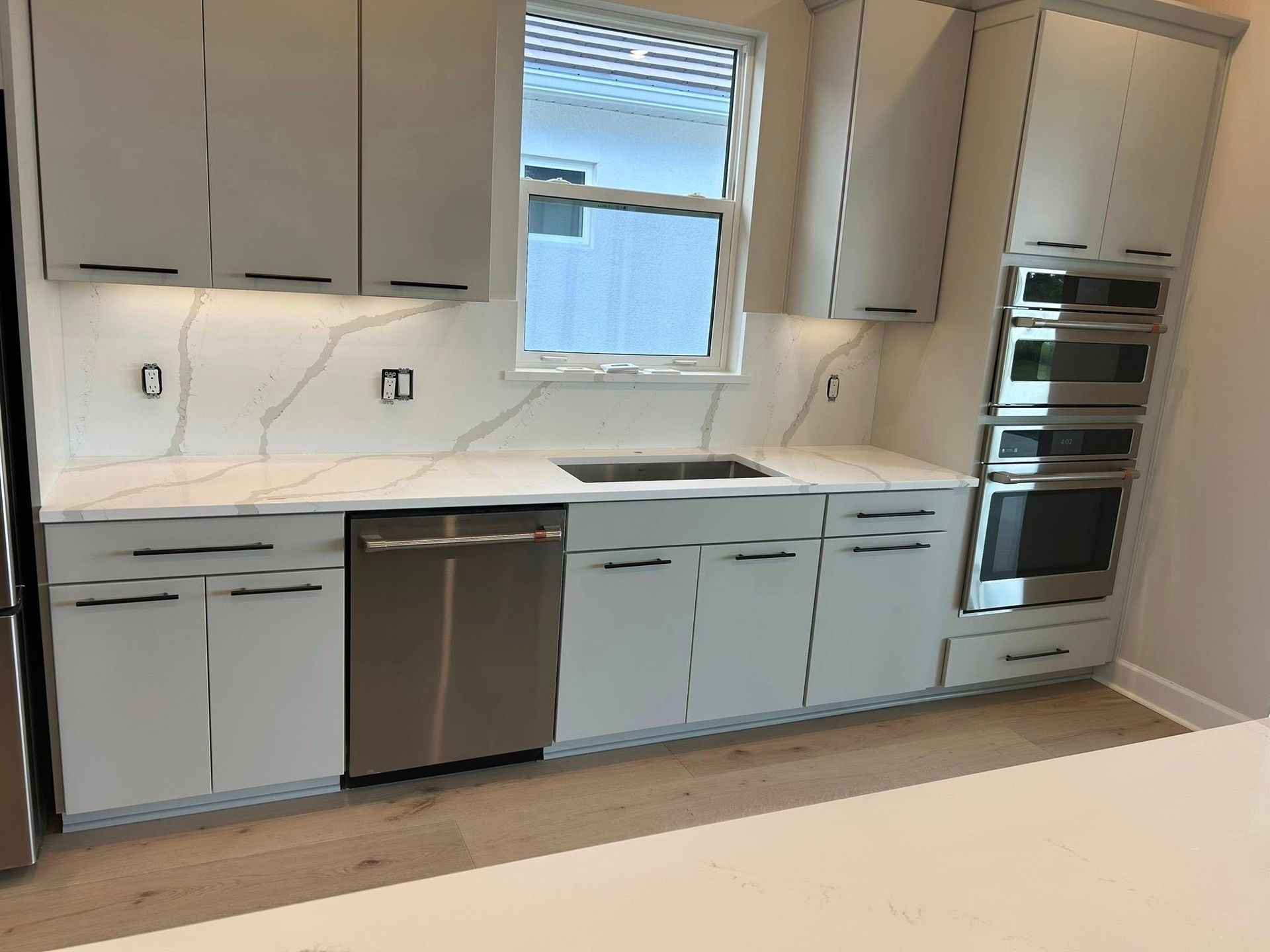 Modern kitchen with white cabinets, stainless steel appliances, and marble countertops.