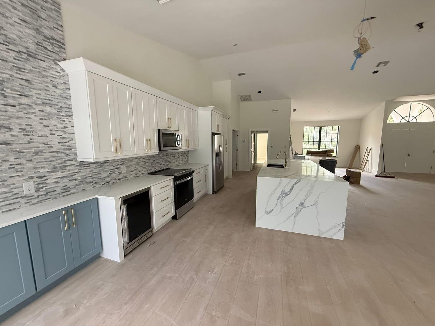 Modern kitchen with white and blue cabinets, marble countertops, and a large island.
