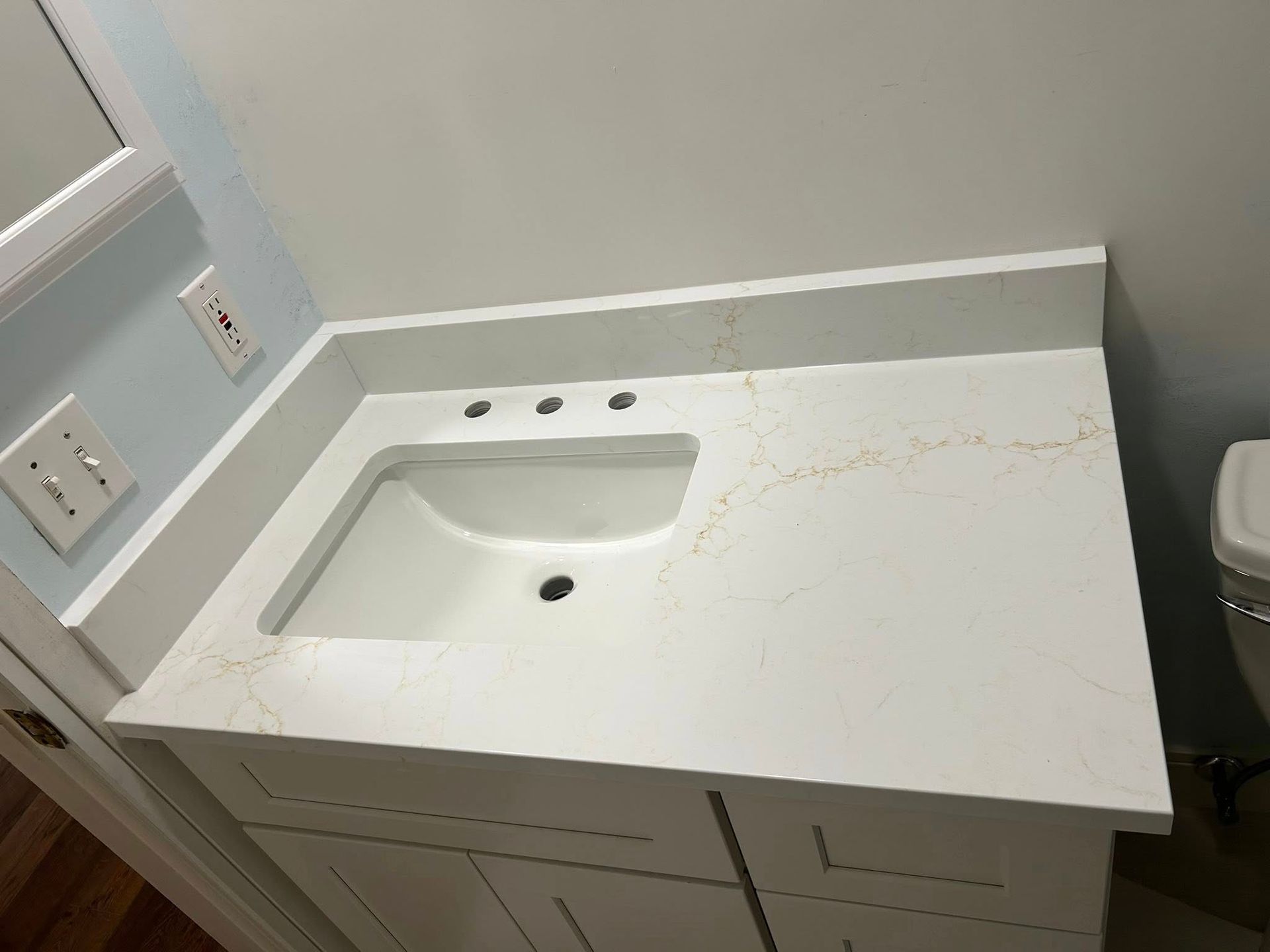 White bathroom vanity with countertop, sink, and faucet holes.