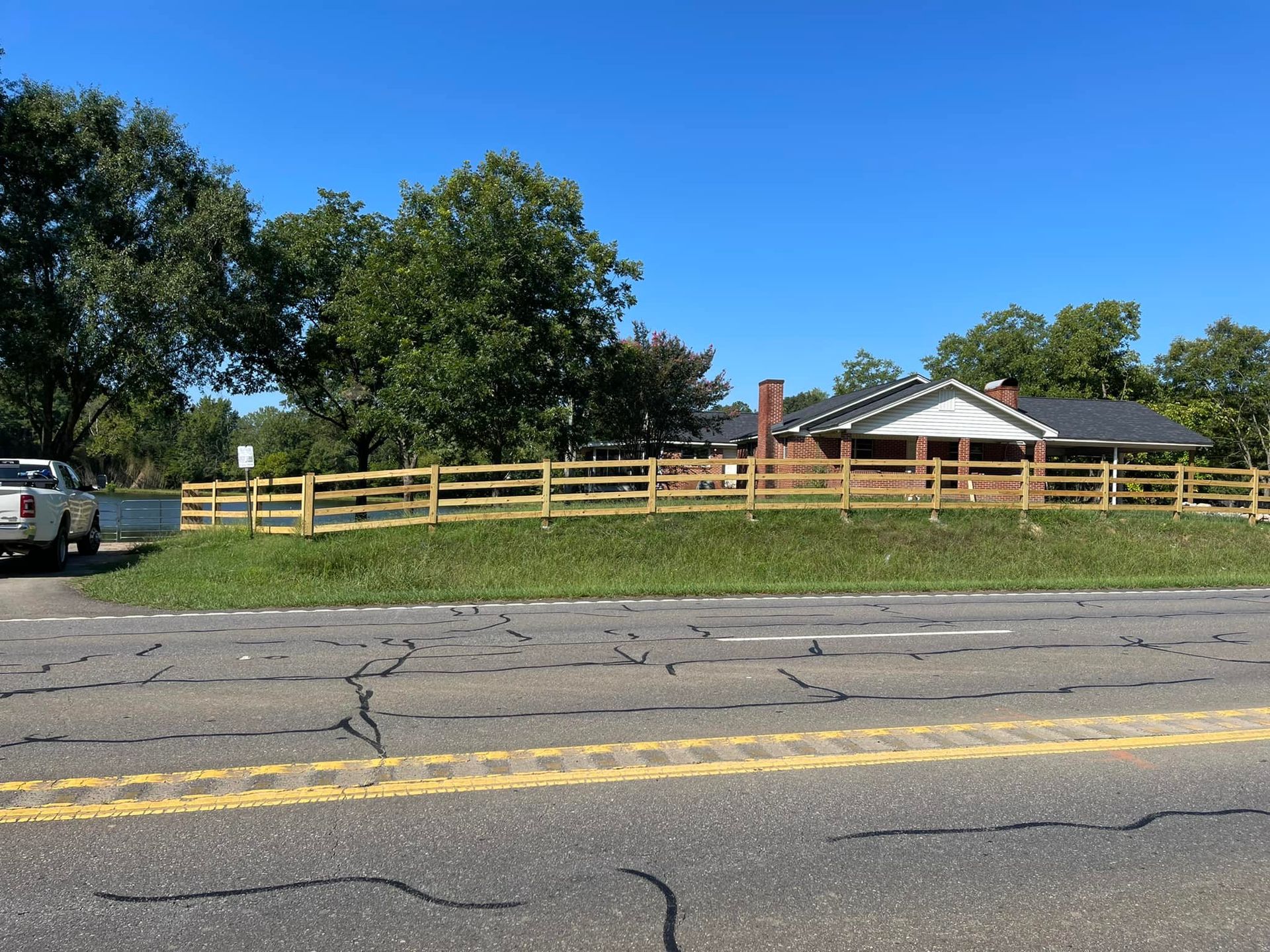A white truck is parked on the side of the road in front of a house