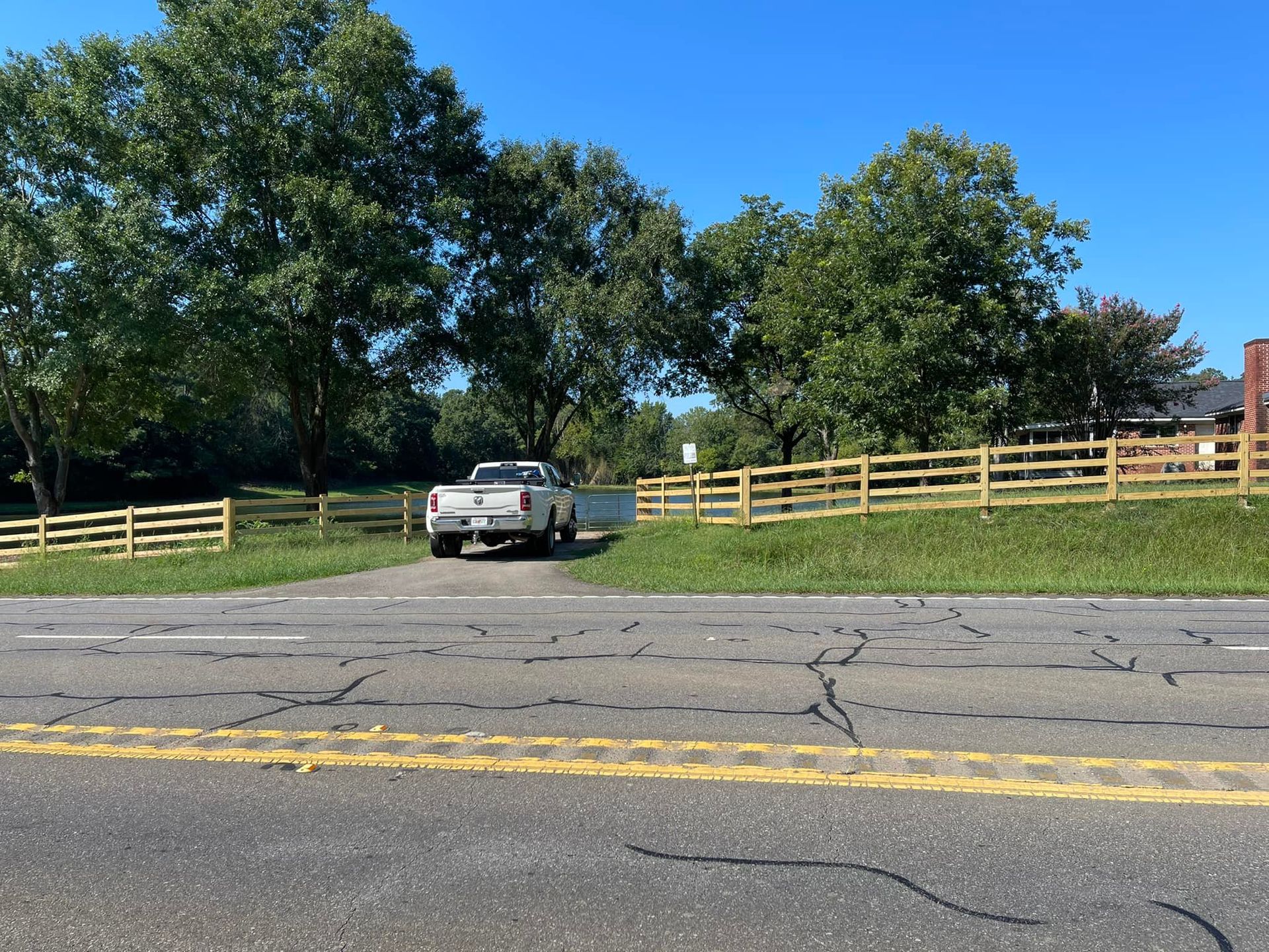 A white truck is parked on the side of the road next to a wooden fence.