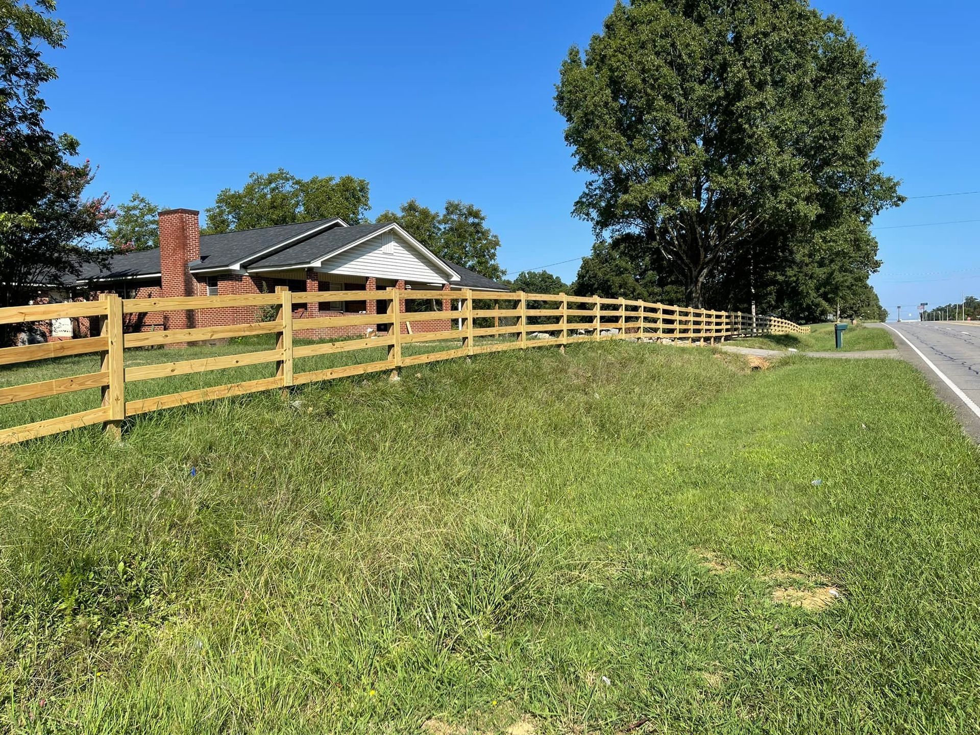 A wooden fence along the side of a road next to a house.