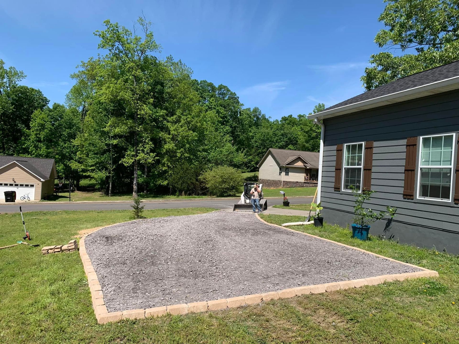 A gravel driveway is being built in front of a house.
