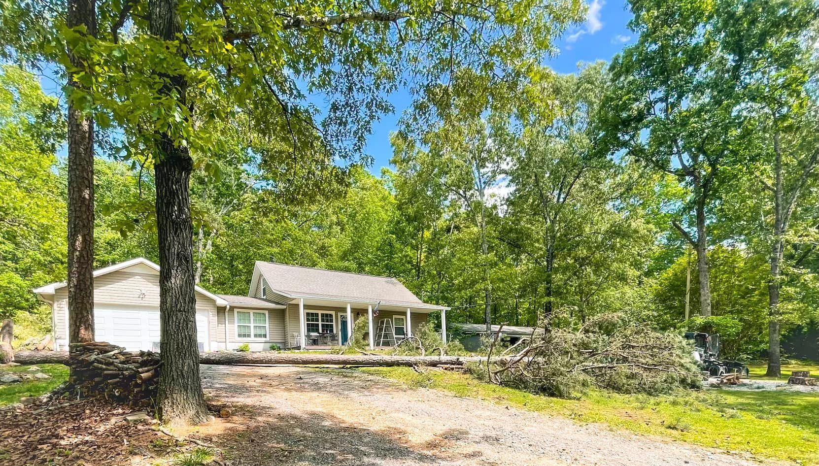 A white house is surrounded by trees and a gravel driveway.