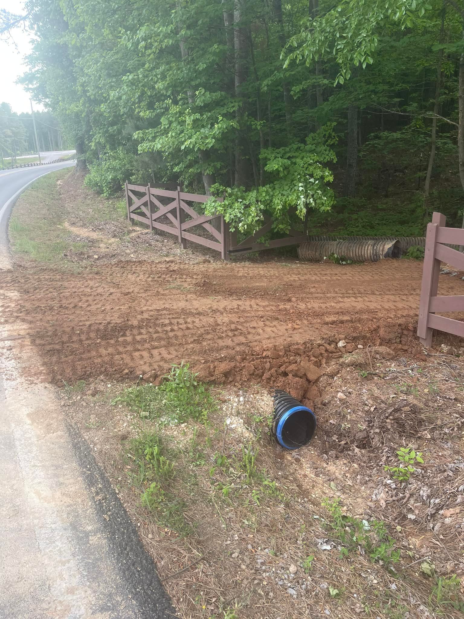 A wooden fence is sitting next to a dirt road.