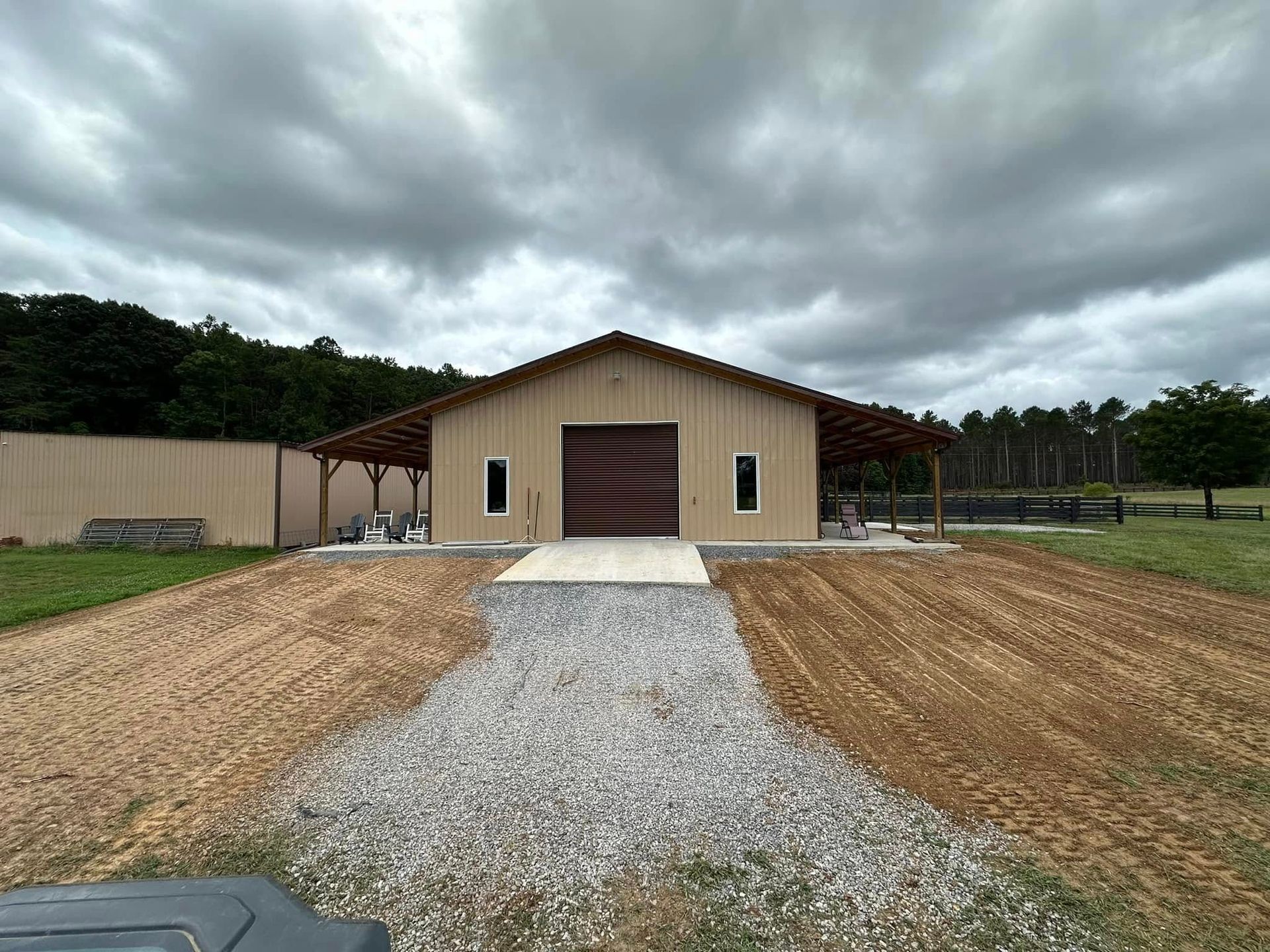 A large barn is sitting in the middle of a dirt field.