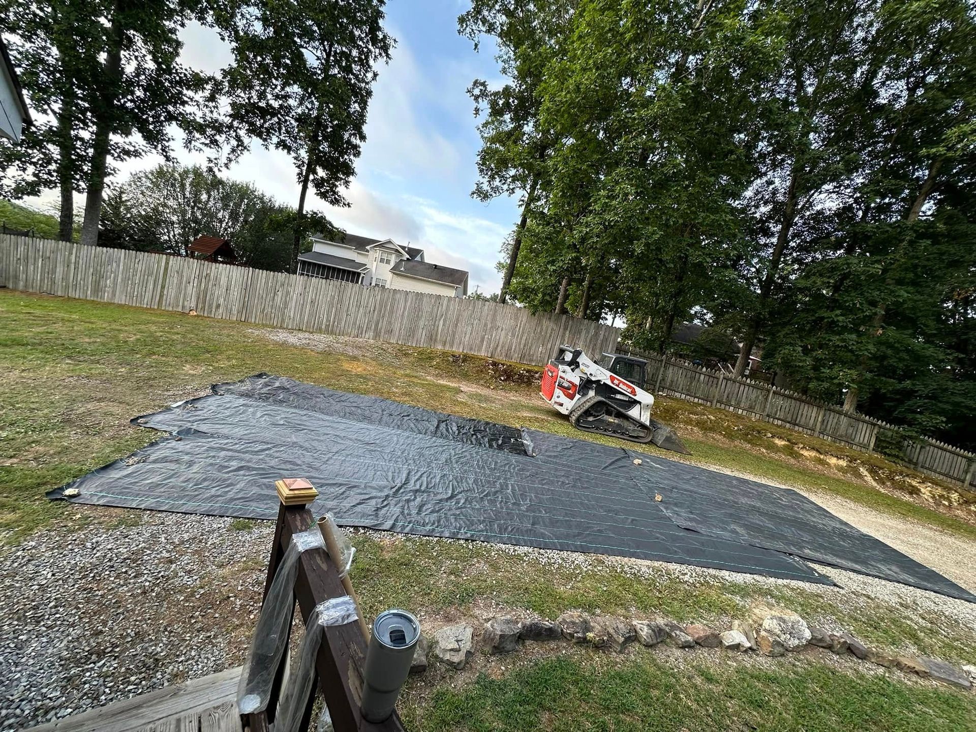A tractor is driving down a dirt road next to a fence.
