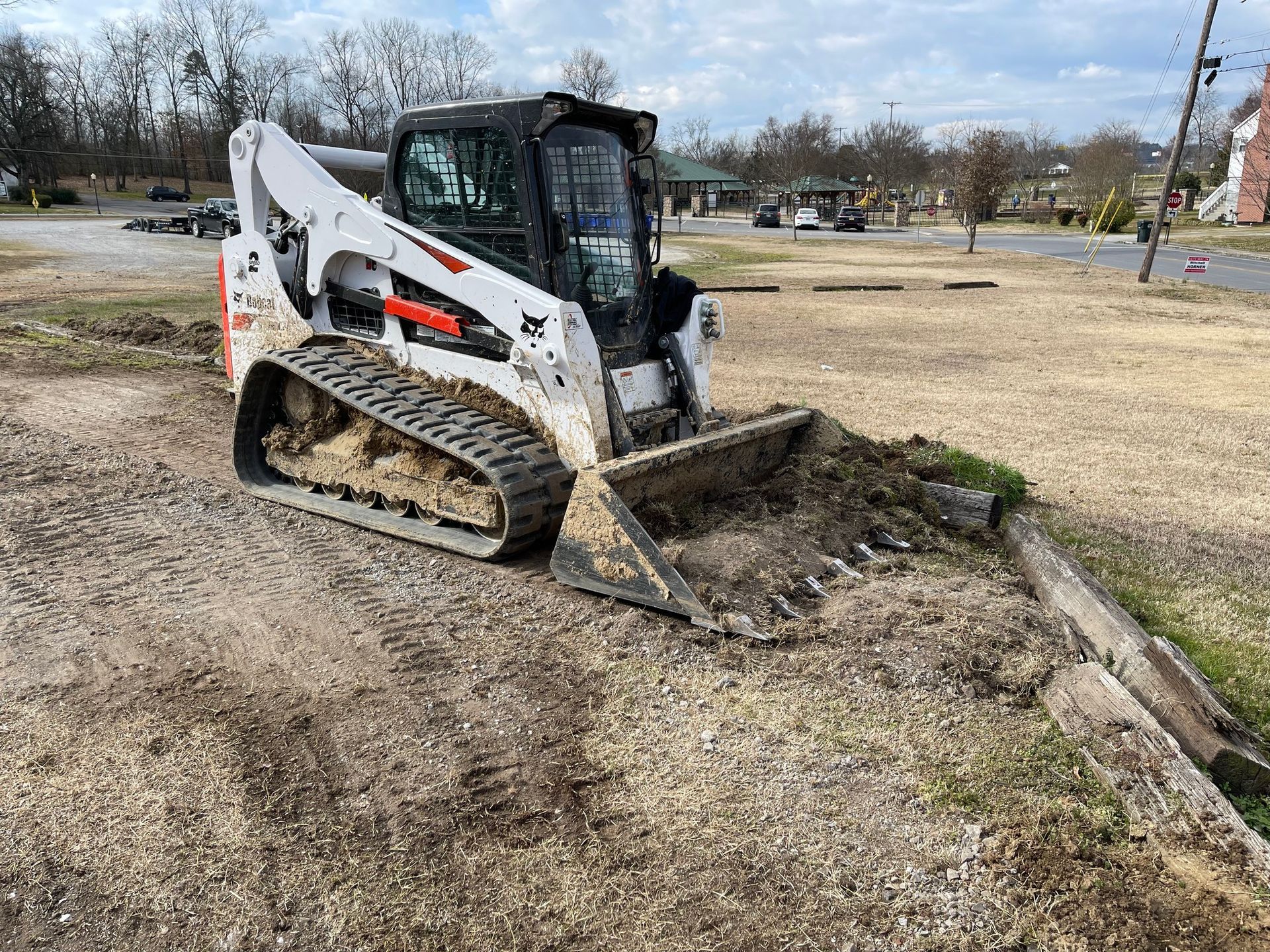 A bulldozer is sitting on top of a pile of dirt in a parking lot.