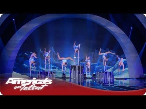 Acrobats performing on a blue-lit America’s Got Talent stage under a giant arch