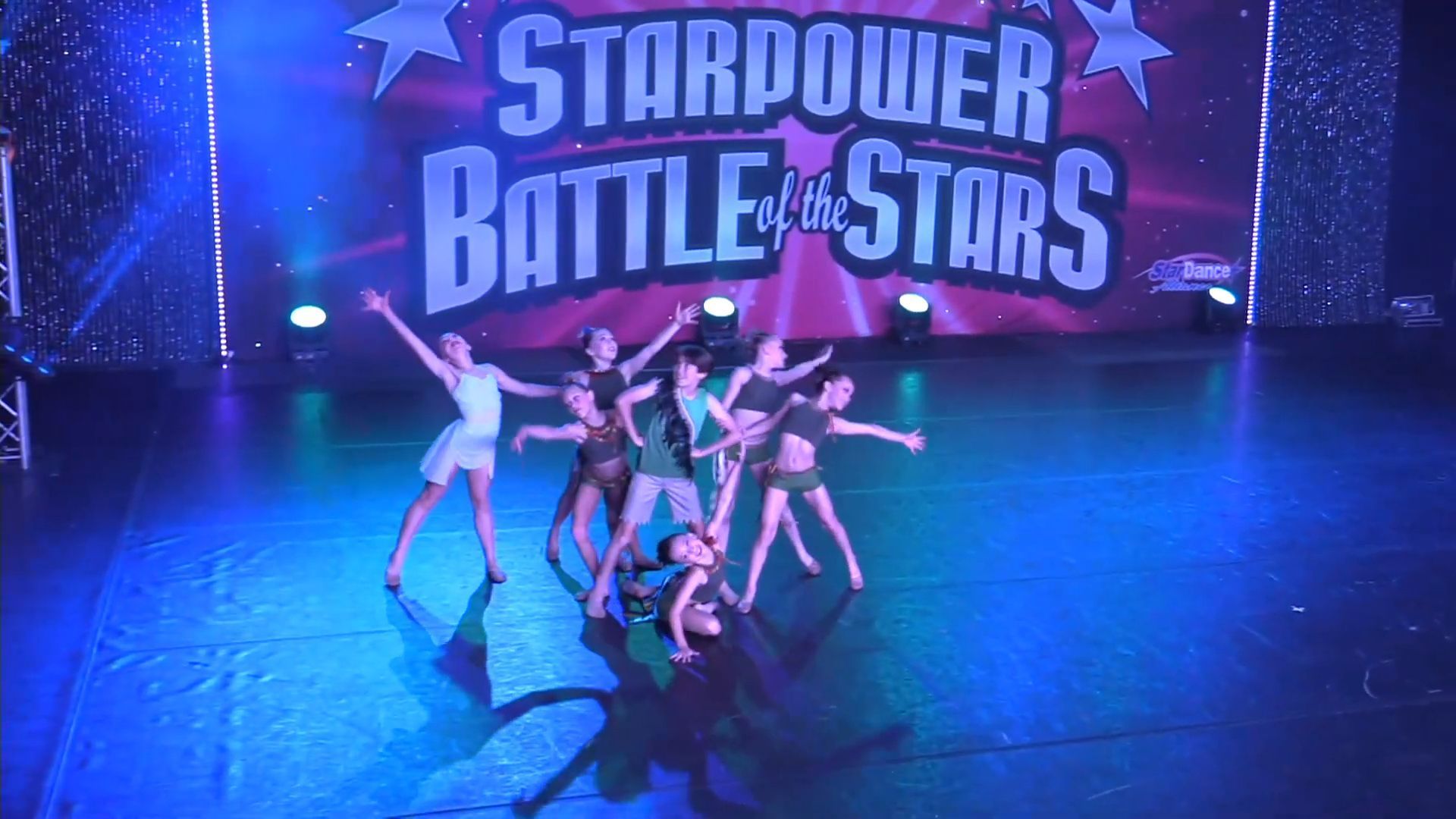 Dancers performing on a blue-lit stage with a “Starpower Battle of the Stars” backdrop