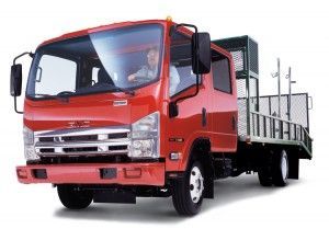 Red GMC truck with a flatbed carrying equipment.