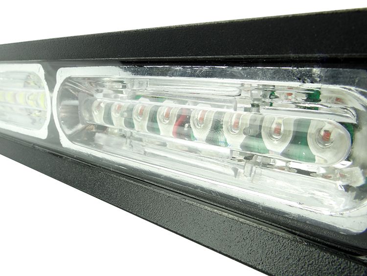 Close-up of a black emergency light bar with clear lenses containing red and white LEDs.