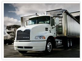White Mack truck hauling a large silver trailer.