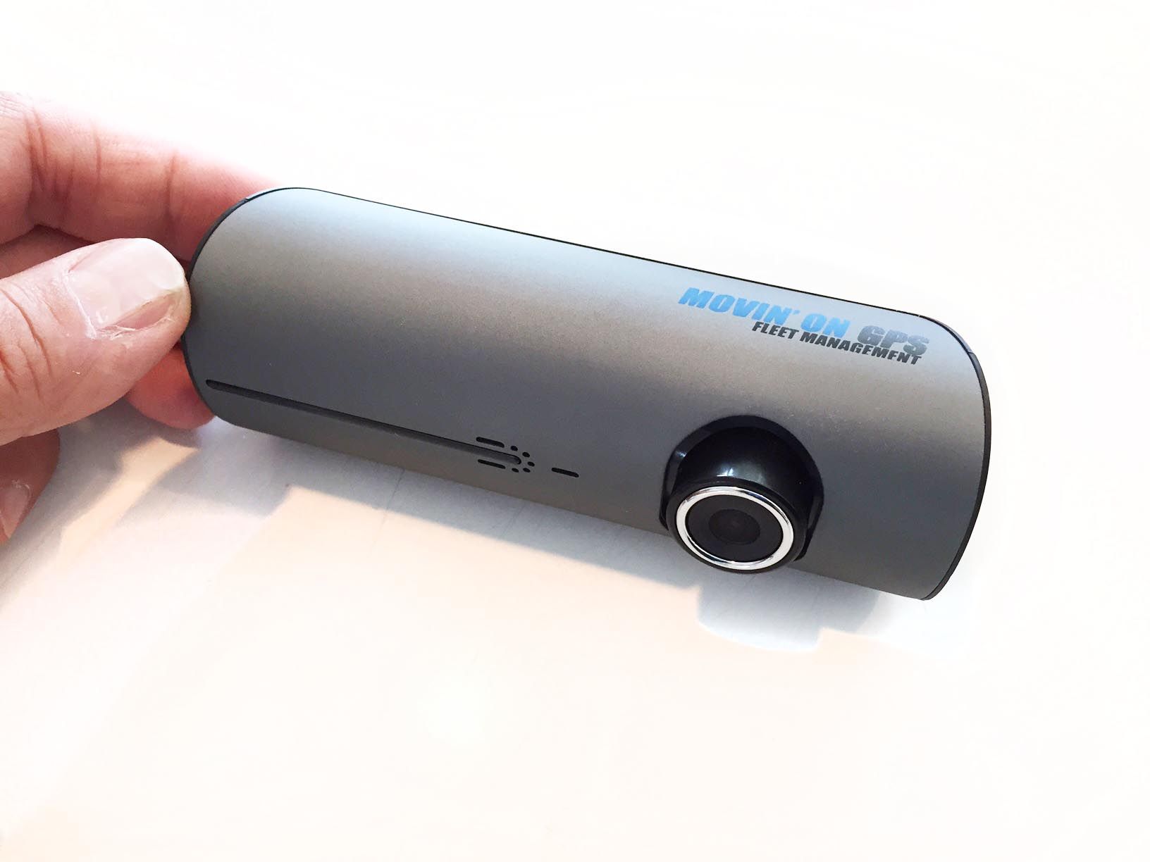 A hand holding a dark gray dashcam with a lens and the words
